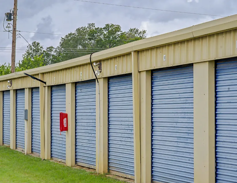 Row of blue roll-up doors on drive-up storage units in Rockdale, TX